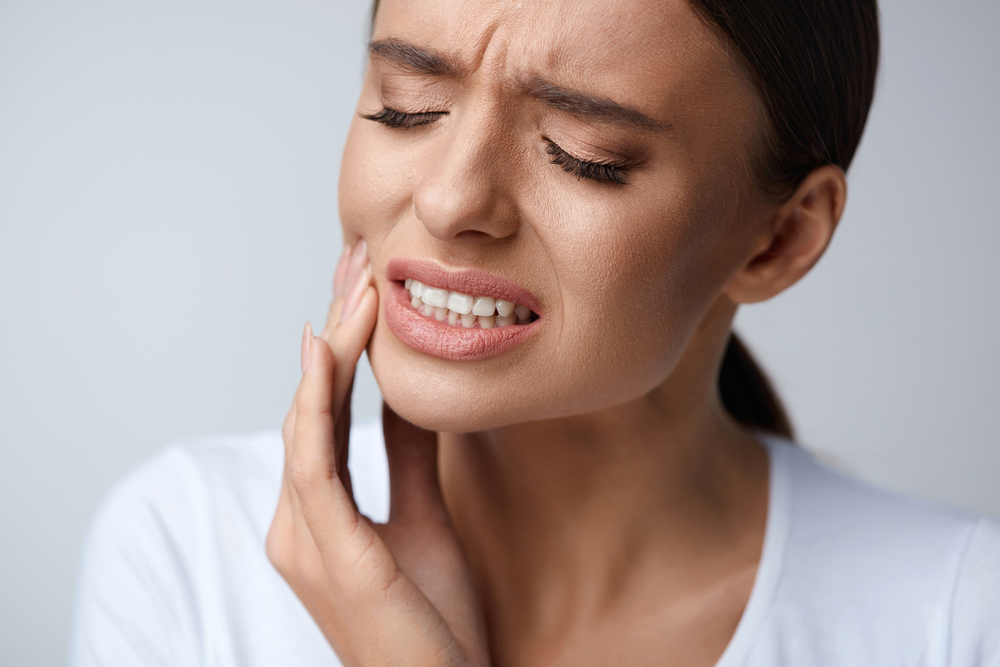 Woman experiencing dental pain clutching mouth